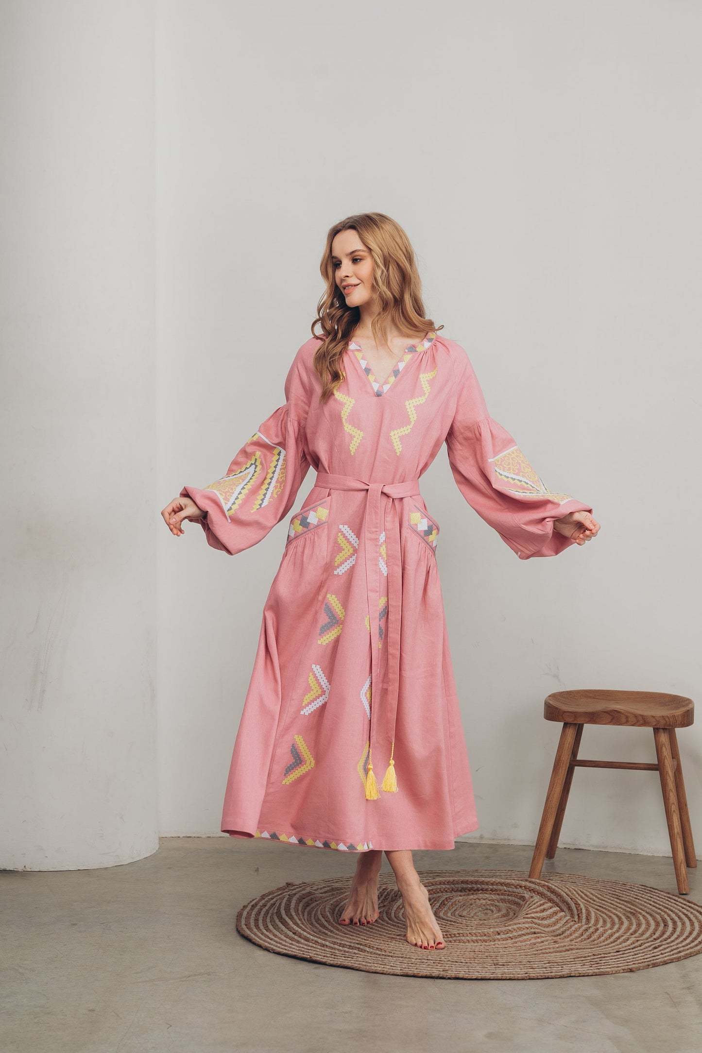 Pink linen embroidered Vyshyvanka dress with Ukrainian boho folk style, featuring a belt and pockets, worn by a model.