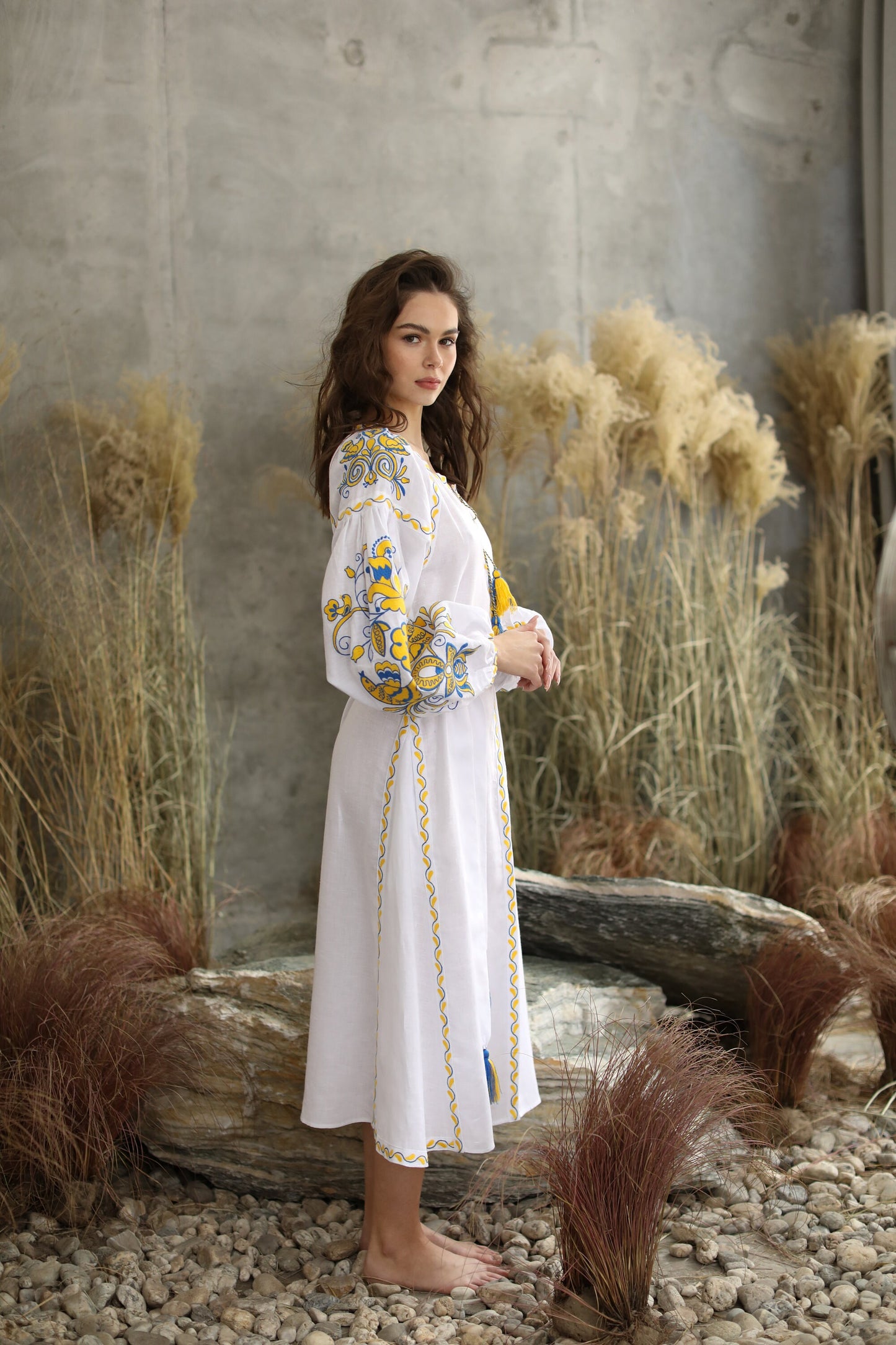Model wearing white linen embroidered 'Victory' wedding dress in Ukrainian Vyshyvanka boho style.