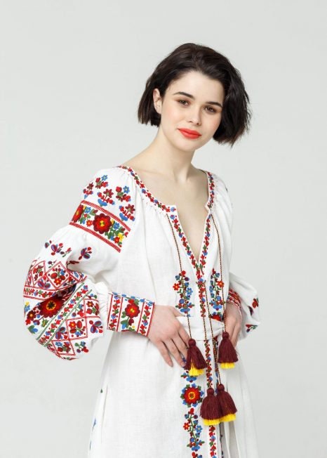 Woman in a white linen embroidered wedding dress, Ukrainian Vyshyvanka boho style, featuring colorful traditional folk patterns.