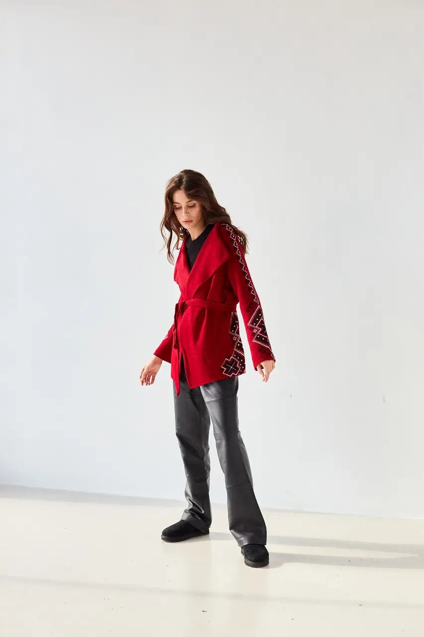 Woman wearing red boho knit cardigan with Ukrainian ornaments, oversized wrap sweater for winter layering.
