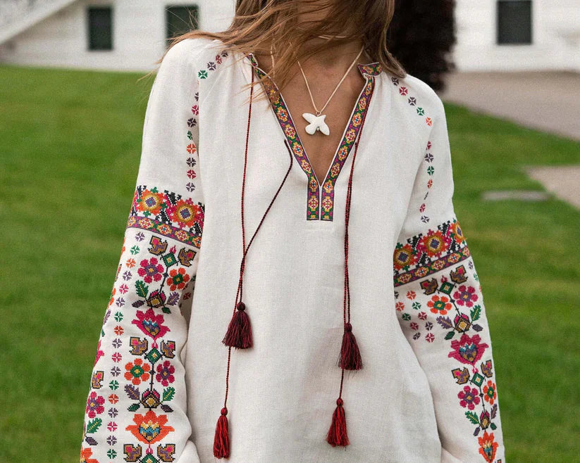 Woman wearing a traditional Ukrainian vyshyvanka with colorful floral embroidery, standing against a historic building backdrop.
