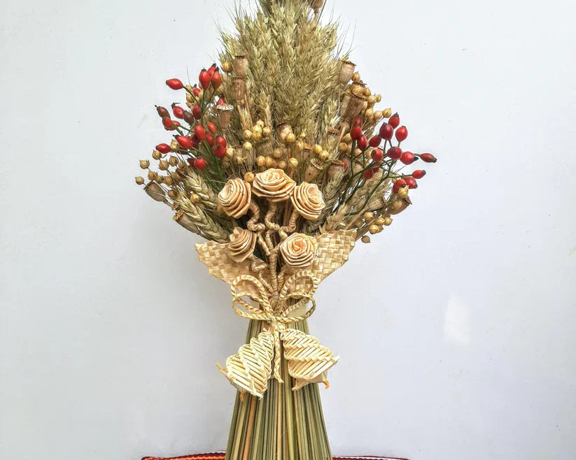 Traditional Ukrainian wheat sheaf Christmas decoration with red berries and intricate straw designs.