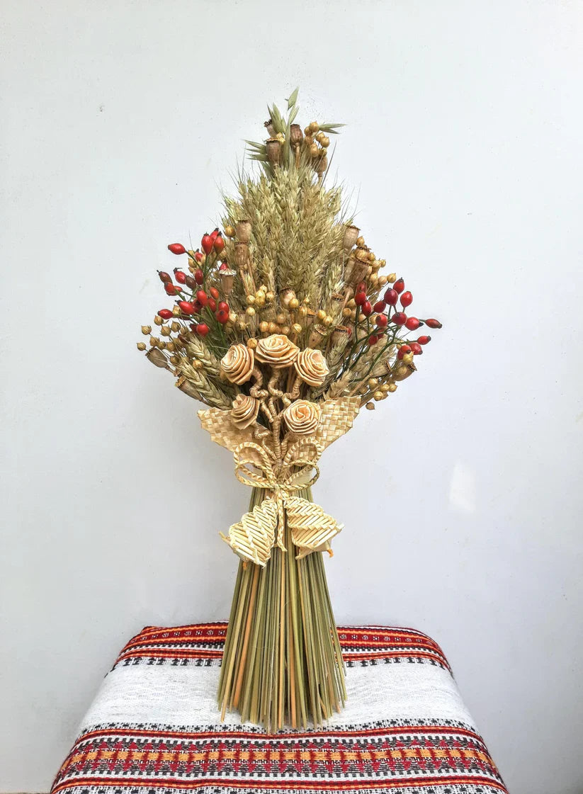 Traditional Ukrainian wheat sheaf Christmas decoration with red berries and intricate straw designs.