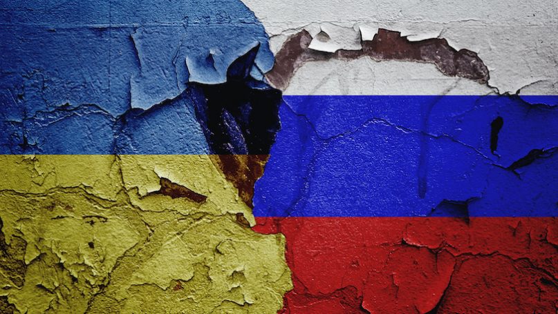 Ukraine and Russia flags painted on a cracked wall symbolizing conflict and tension.