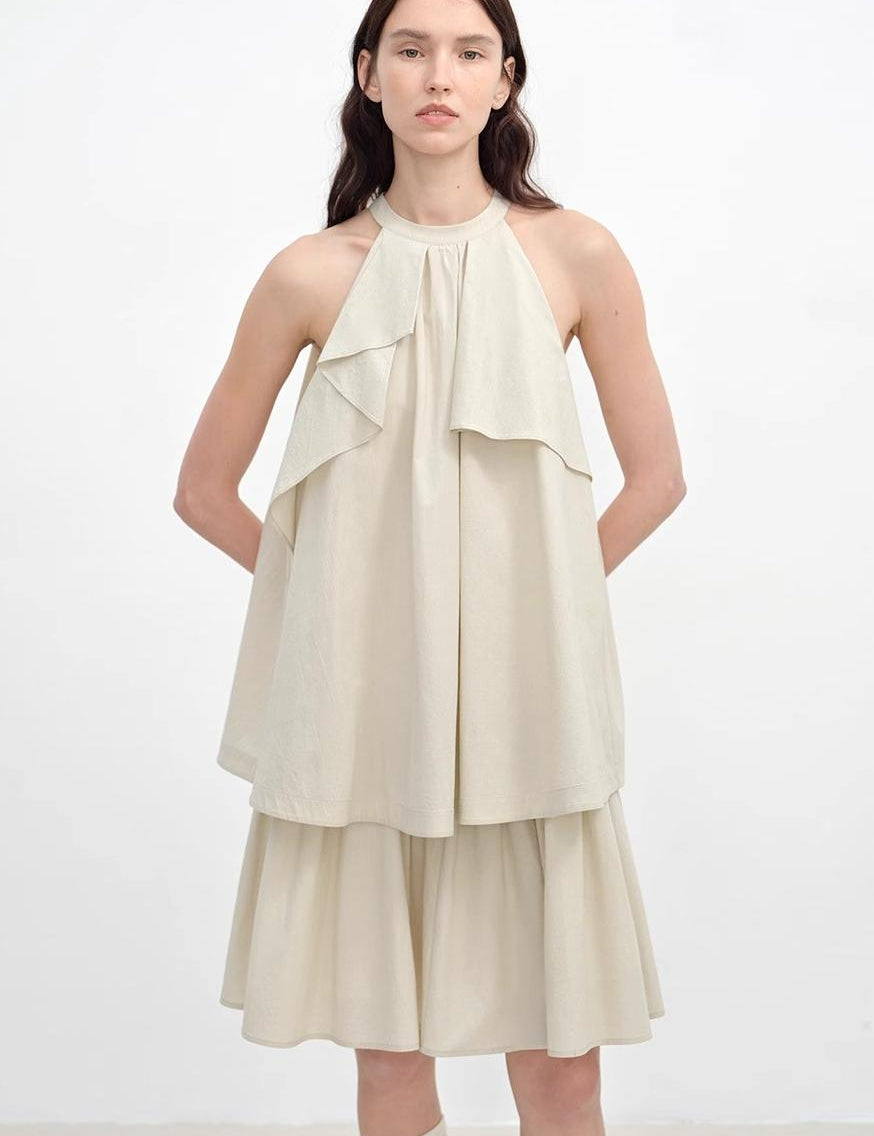 Model wearing Islanda Textured Cotton Halter Dress with asymmetric pleated neckline and mid-calf skirt, showcasing elegant A-line shape.
