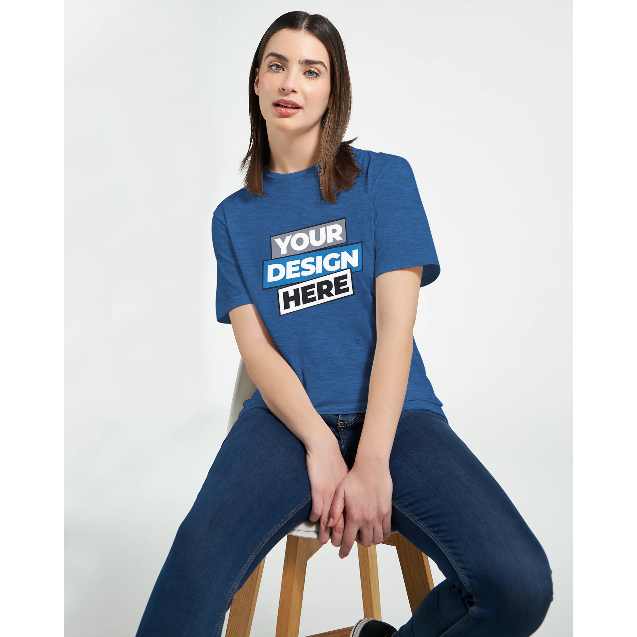 Woman wearing a blue Zalmera cotton t-shirt with customizable print design, seated on a stool, showcasing casual style.
