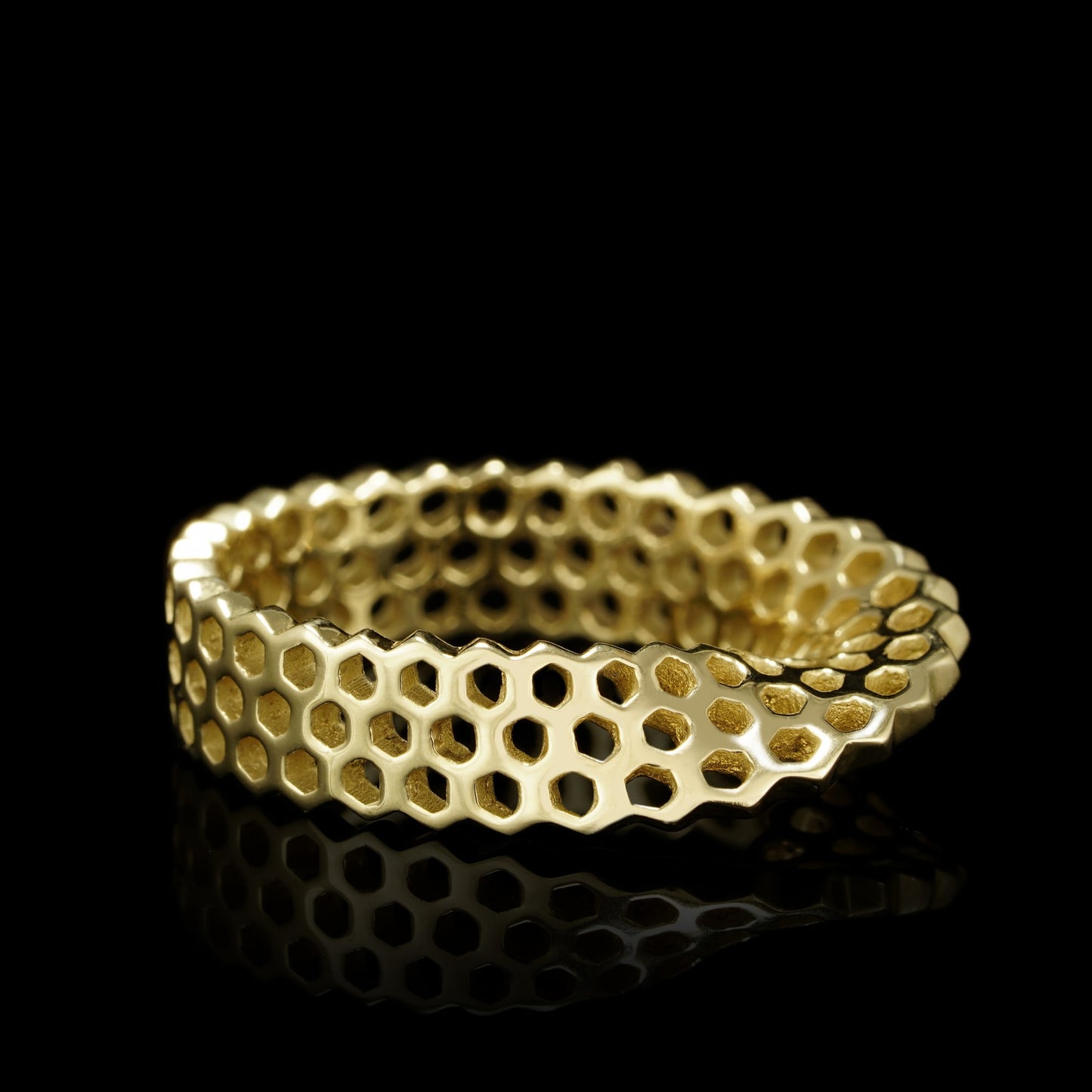 Elegant gold ring with honeycomb pattern design on a black background