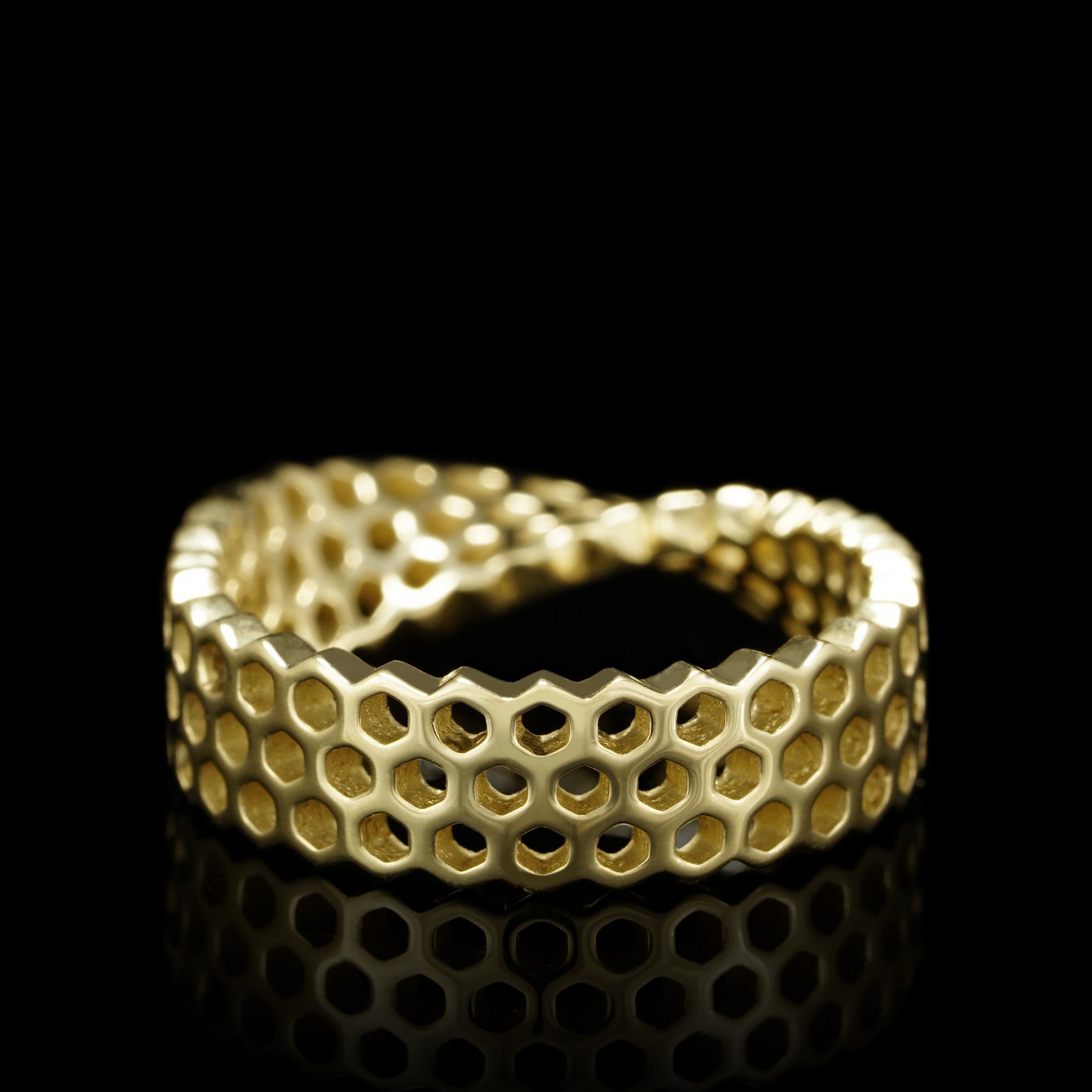 Luxurious yellow 14K gold "Eternal Ribbon" ring with Mobius ribbon design, showcasing intricate honeycomb pattern.