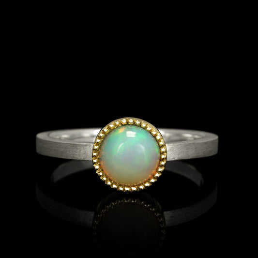 Cosmic Horizon ring with opal gemstone set in sterling silver and 14K yellow gold against a black background.