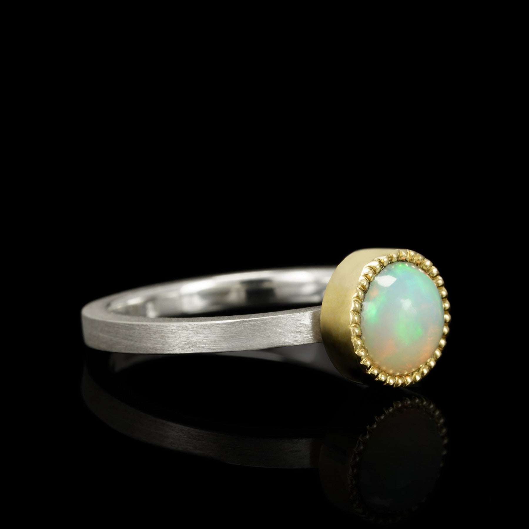 Sterling silver and 14K gold "Cosmic Horizon" ring with mesmerizing 7mm opal, celestial-inspired design against black background.