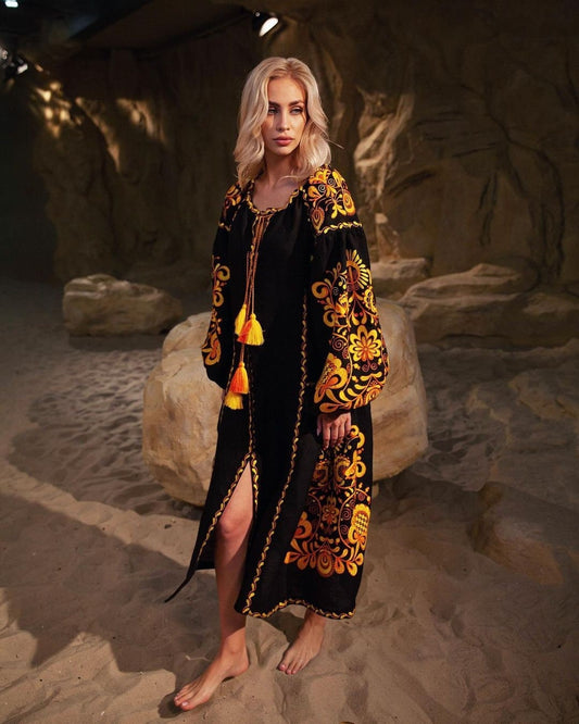 Model wearing black boho linen dress with vibrant Ukrainian embroidery, featuring a Sacred Life Tree motif and ethnic style design.