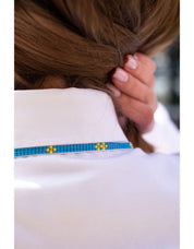 Close-up of a woman wearing a handmade blue and yellow Ukrainian gerdan necklace on a white shirt.