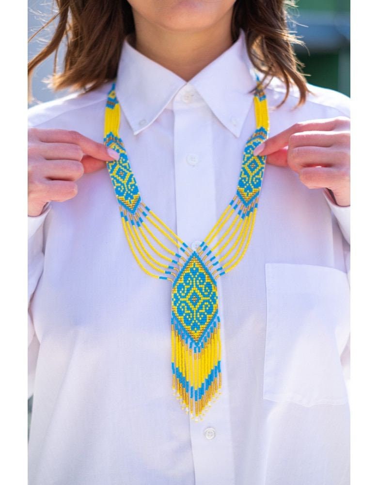 Woman wearing handmade Ukrainian gerdan necklace with yellow and blue beads, symbolizing cultural pride and heritage.
