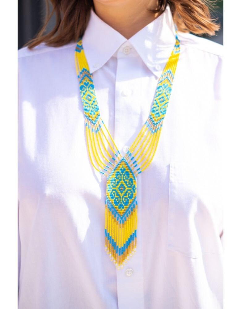 Yellow and blue handmade Ukrainian gerdan necklace on white shirt, traditional beaded folk jewelry symbolizing cultural pride.