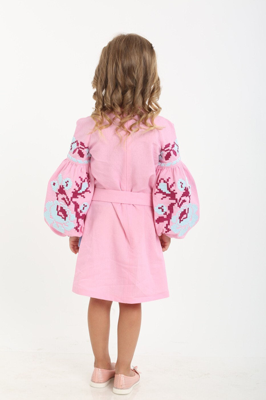 Back view of a girl wearing a pink Ukrainian vyshyvanka dress with floral embroidered sleeves, made from 100% natural linen.