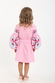 Back view of a girl wearing a pink Ukrainian vyshyvanka dress with floral embroidered sleeves, made from 100% natural linen.
