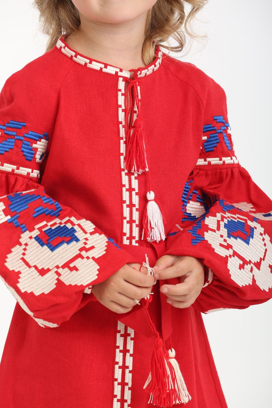 Girl wearing a red linen vyshyvanka dress with floral embroidery and tassels.