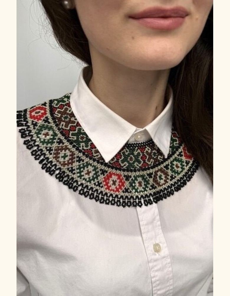 Woman wearing a handmade Ukrainian Kryza necklace with green, beige, and red beads, styled as a traditional collar.