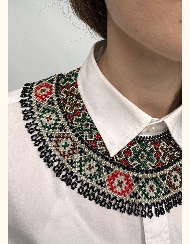 Green beaded Ukrainian Kryza necklace in traditional folk style adorning a white shirt collar.