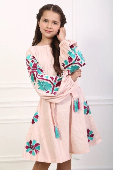 Girl wearing 2025 pink linen embroidered Ukrainian boho dress with folk-style patterns and belt, showcasing elegance and tradition.