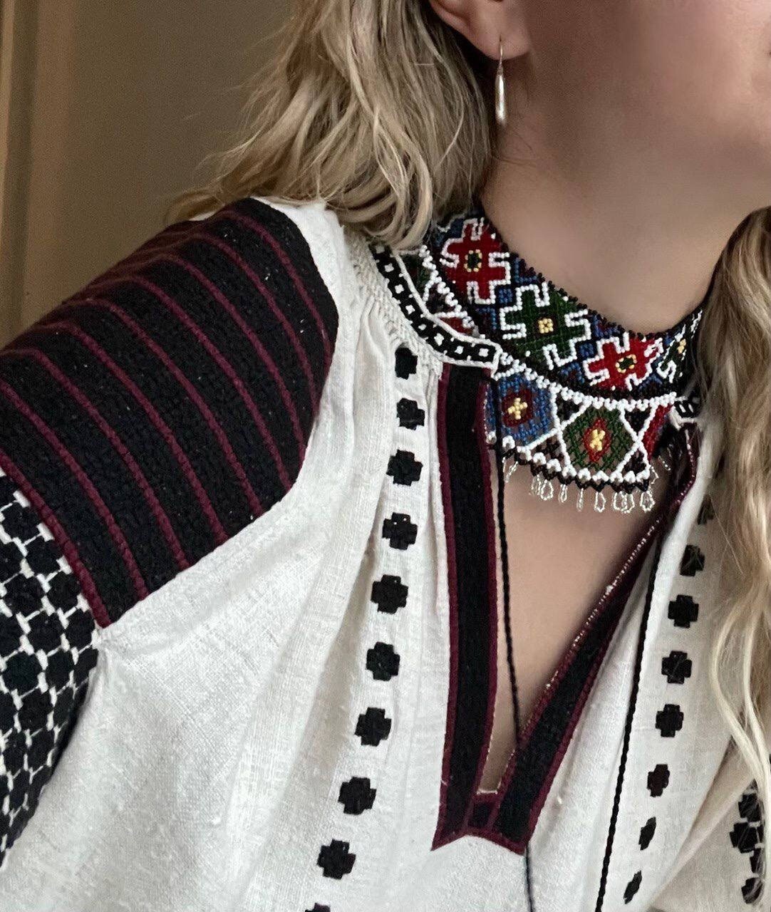 Woman wearing traditional Ukrainian Sylyanka beaded collar necklace with geometric patterns.