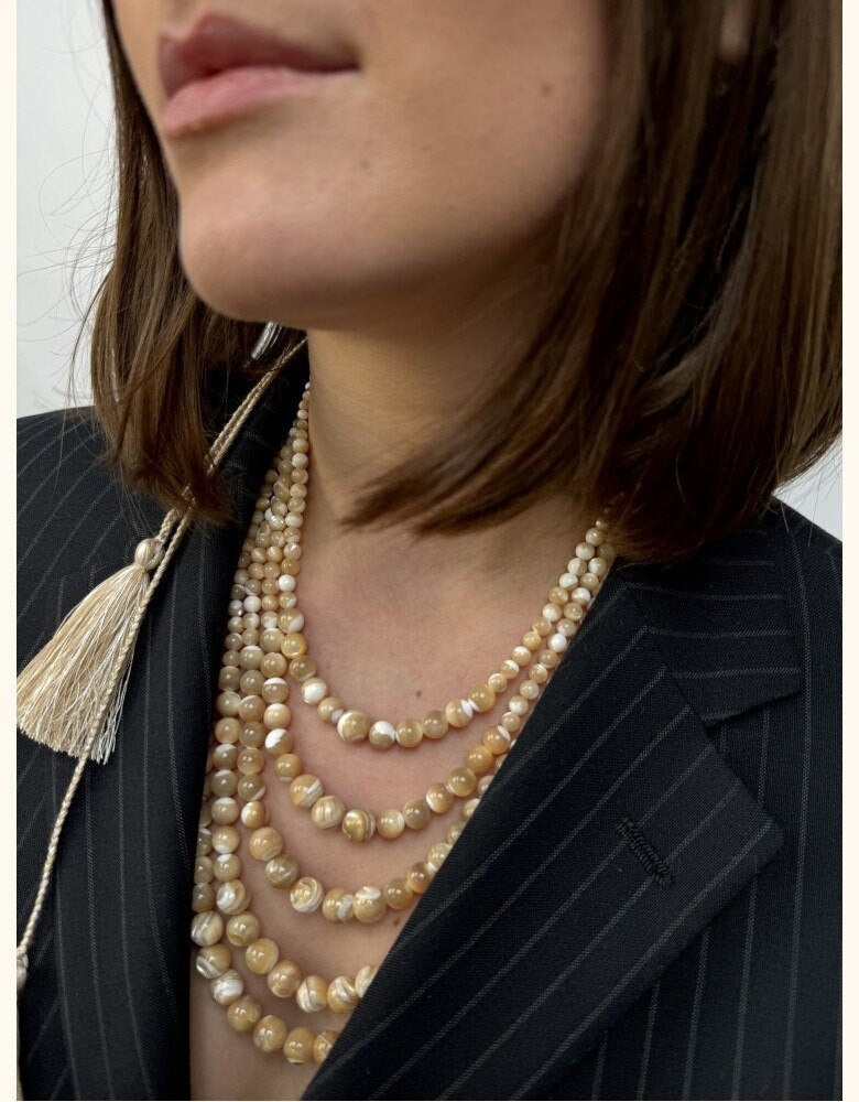 Five-strand golden mother-of-pearl necklace, elegant Ukrainian folk jewelry, paired with a black pinstripe suit.