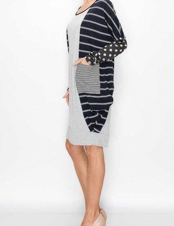 Model wearing Kylara Color‑Block Balloon Dress with stripes and polka dots, showcasing side view and front patch pockets.