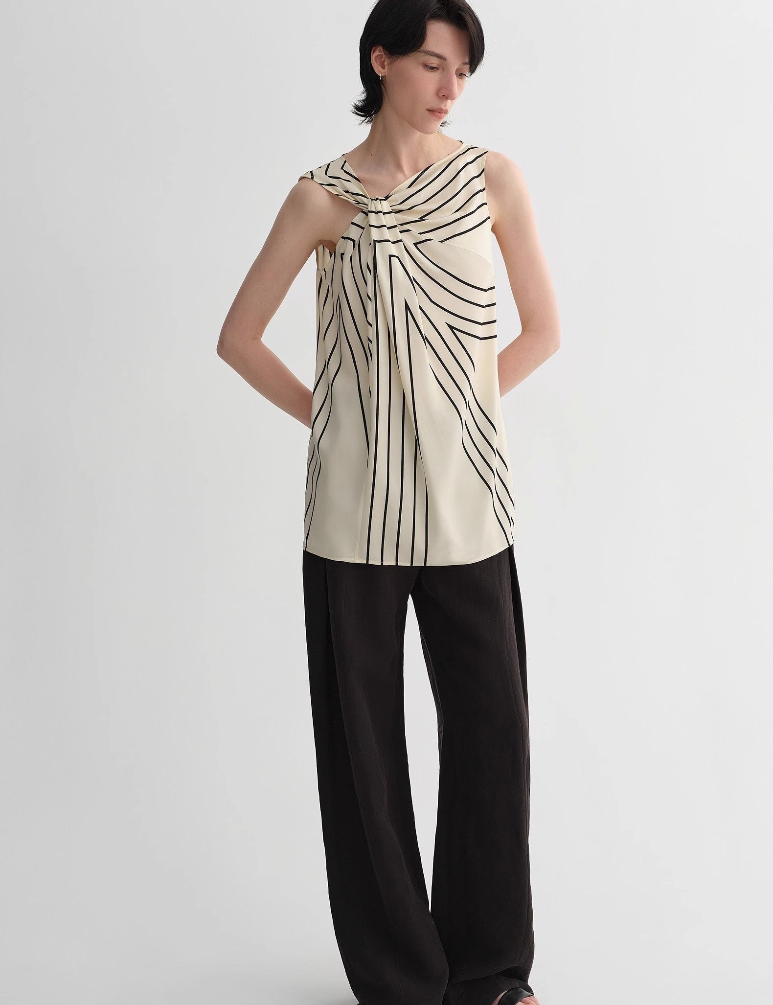 Woman wearing Seravelle Twisted Silk Vest with geometric print, sleeveless design, and draped collar, ideal for city minimalism style.