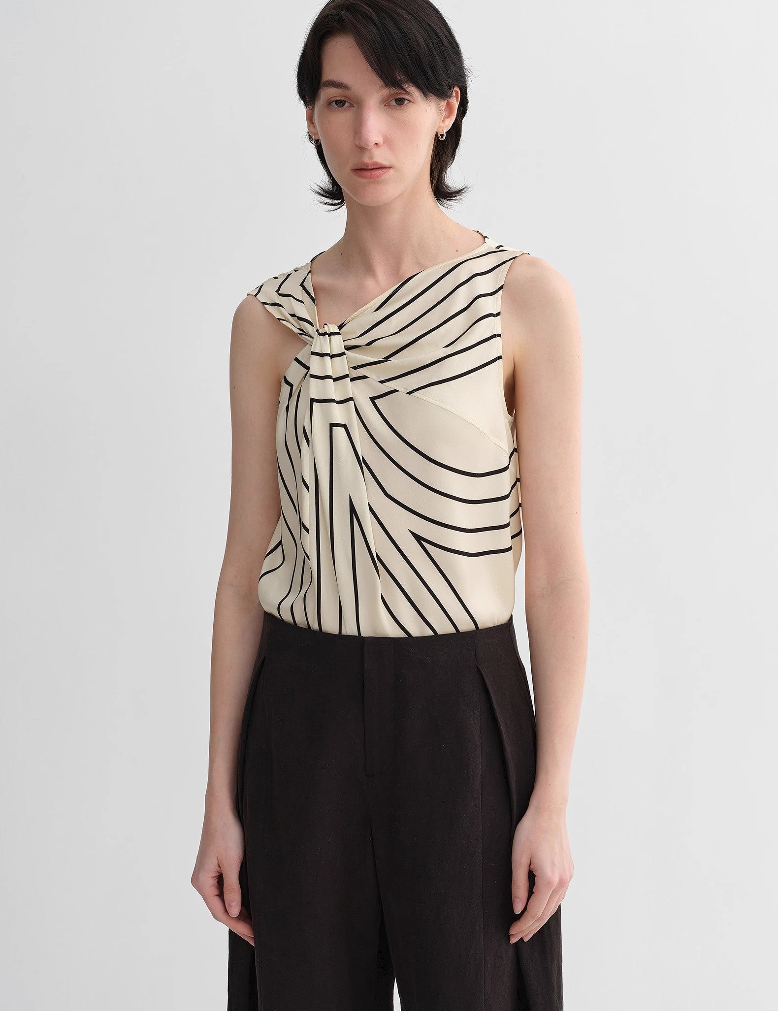 Woman wearing Seravelle Twisted Silk Vest with geometric print, draped collar, and slim fit, showcasing elegant city style.