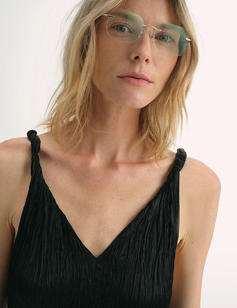 Model wearing Veylani Wave-Pleat V-Neck Dress, featuring dynamic pleats and a deep V-neckline, crafted from lustrous Eastman NAIA acetate.