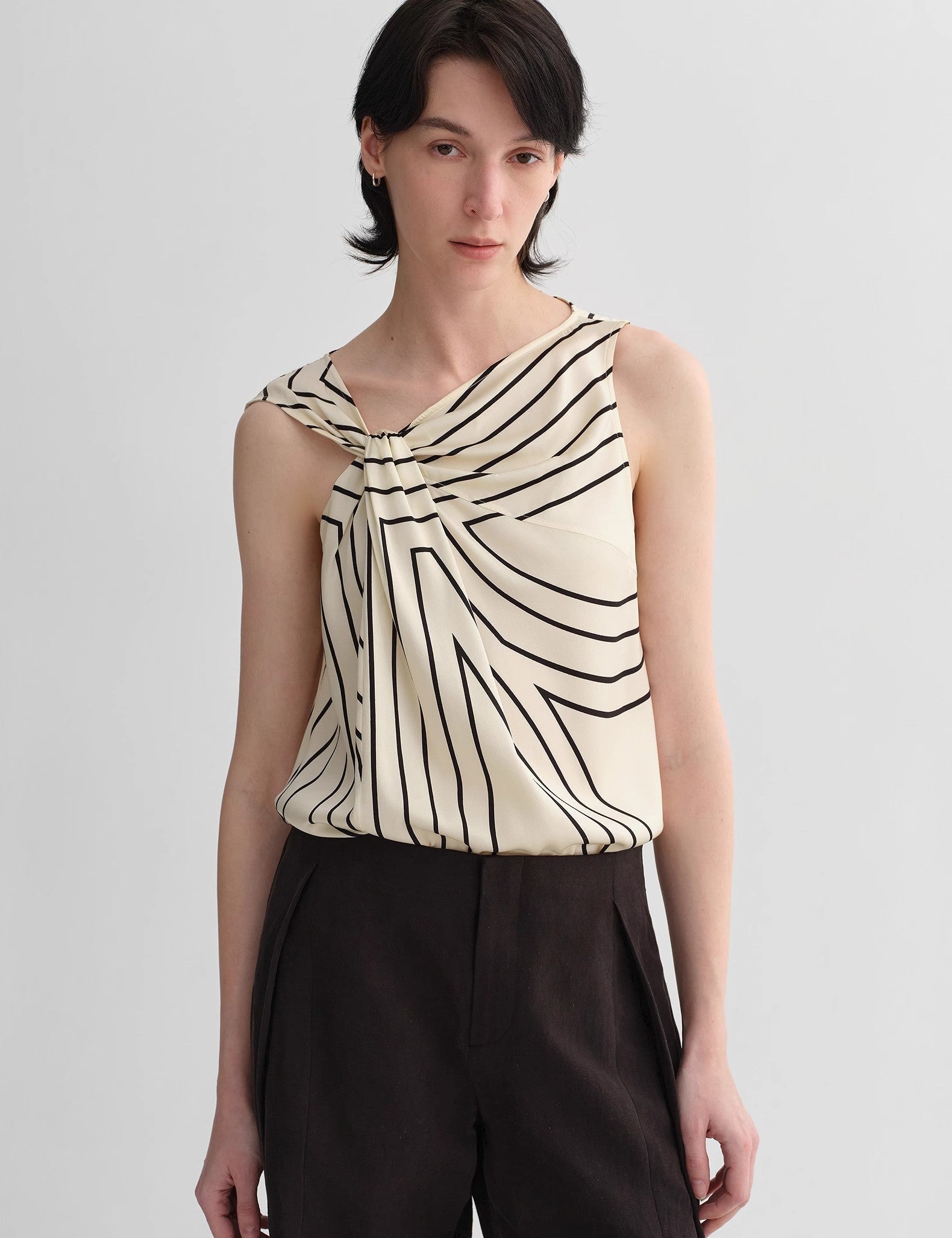 Model wearing Seravelle Twisted Silk Vest with asymmetrical design and geometric print in contrasting tones, embodying urban minimalism.