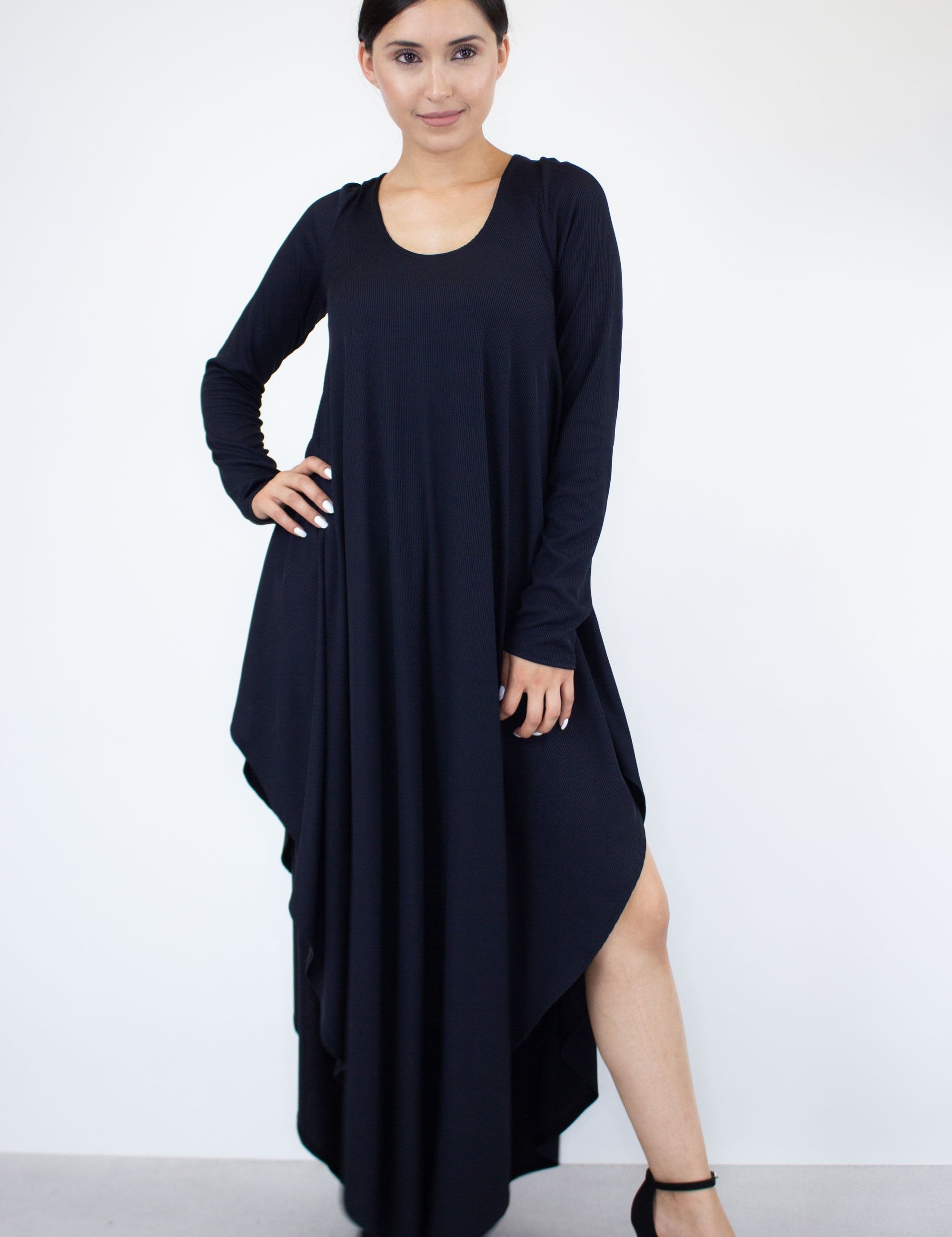 Woman wearing an Eloura Asymmetric Maxi Dress with a soft drape, long sleeves, and asymmetric hemline for elegant day-to-evening style.