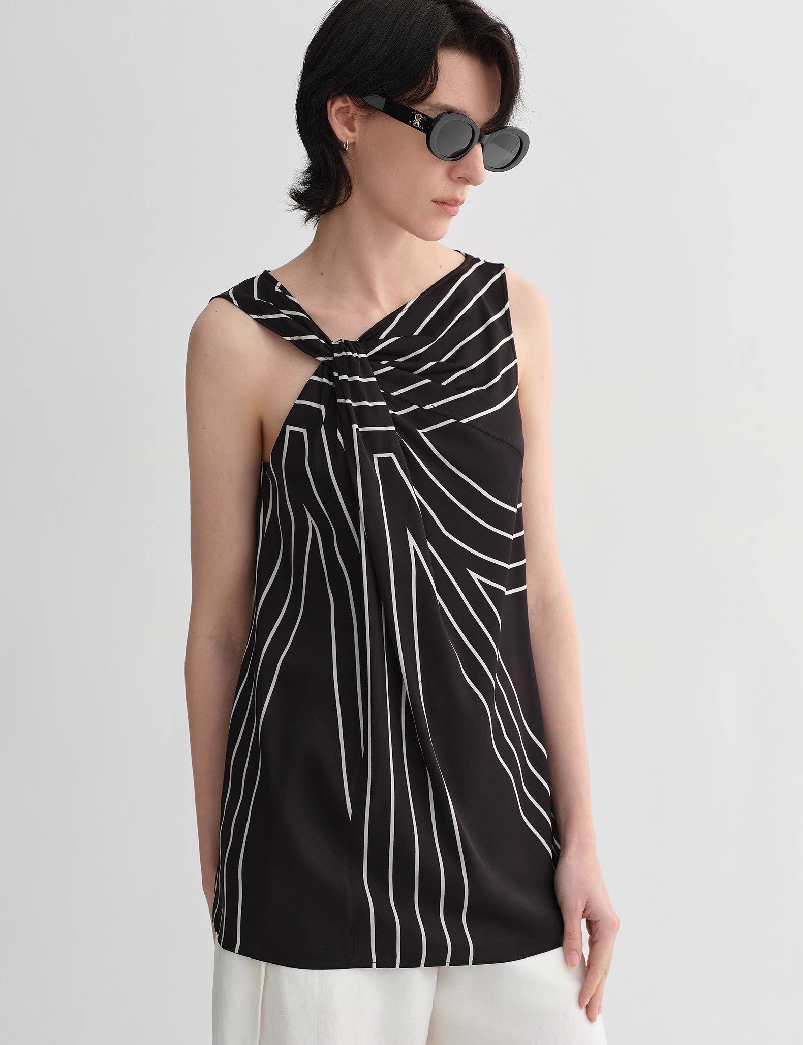 Woman wearing Seravelle Twisted Silk Vest with geometric print and draped collar, embodying city minimalism and refined elegance.