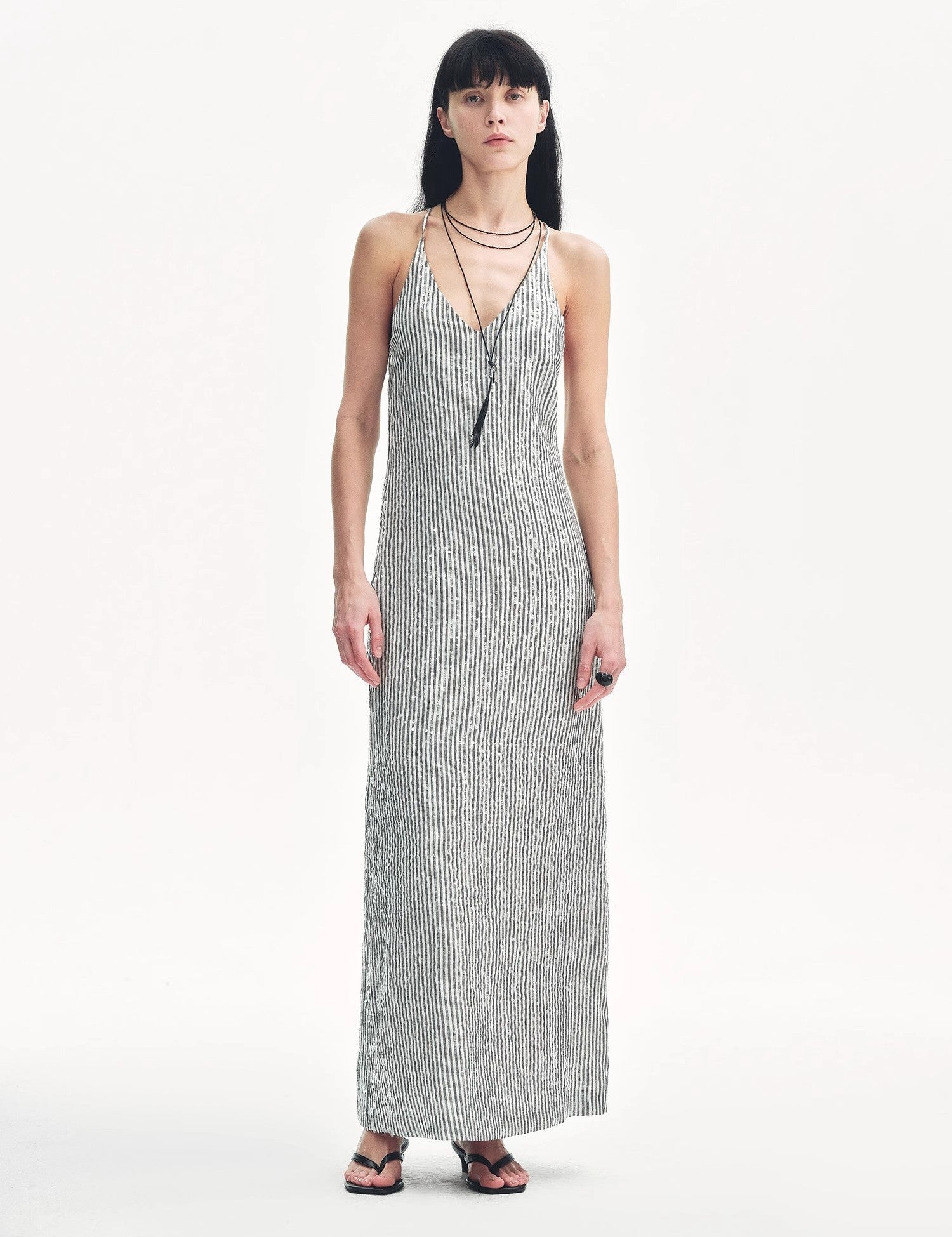 Woman wearing Astrenya Sequin Linen Maxi Dress with V-neck and thin straps, showcasing all-over sequin embroidery and open back design.