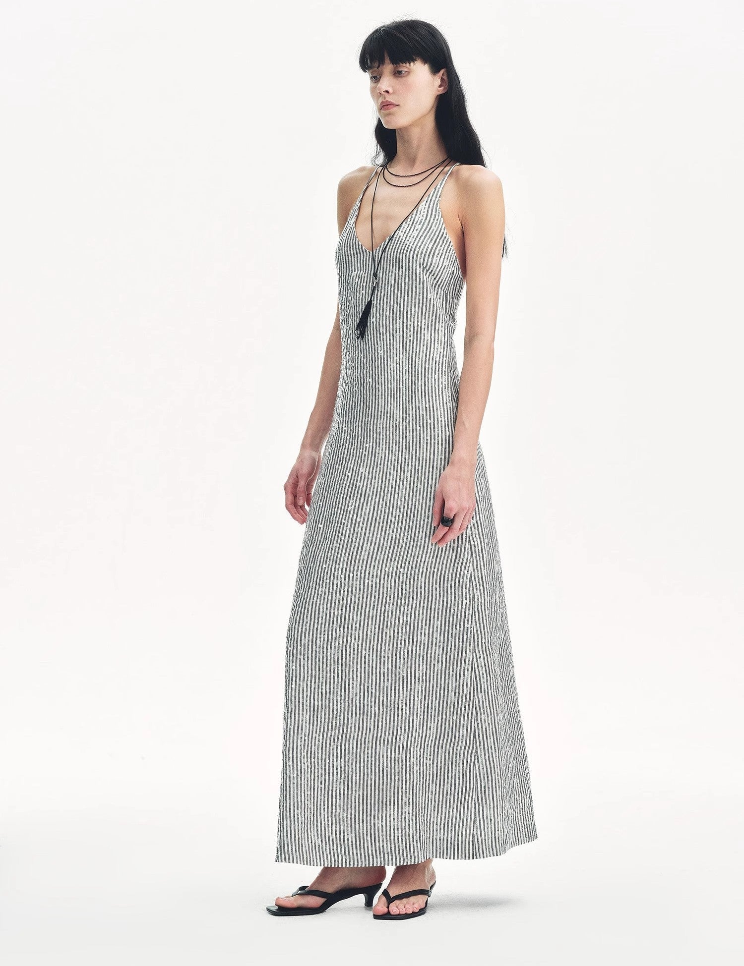 Woman wearing Astrenya Sequin Linen Maxi Dress with V-neckline and thin straps, showcasing shimmering sequin embroidery.