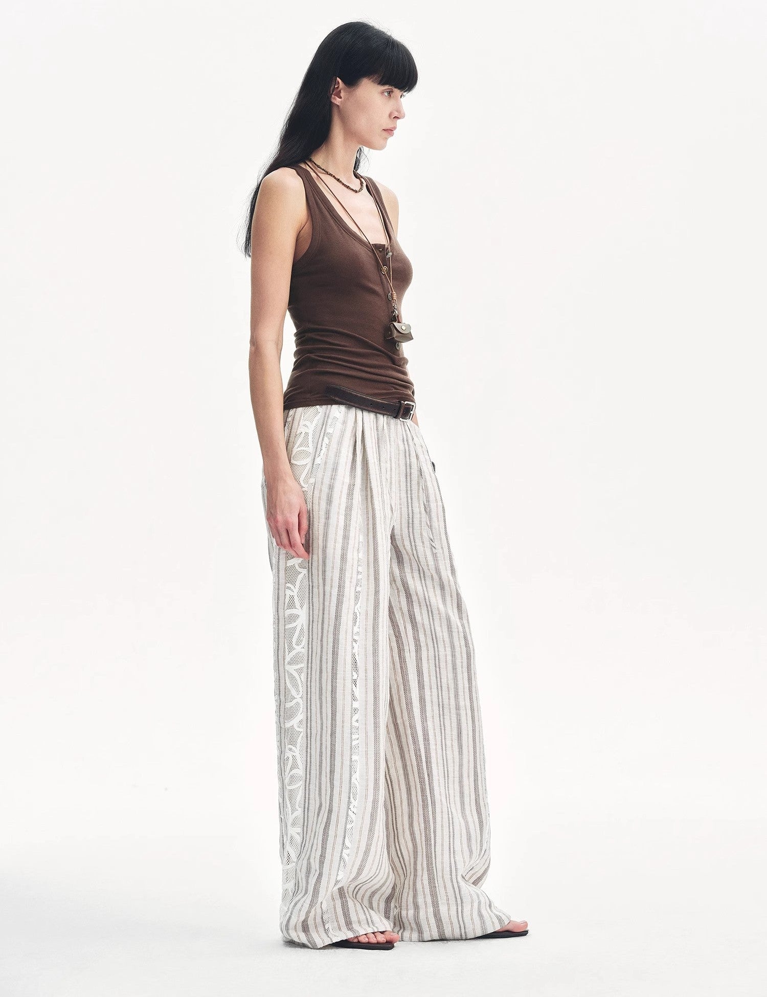 Model wearing Lureva U-Henley Vest with minimalist silhouette and Henley neckline, paired with wide-striped white pants.