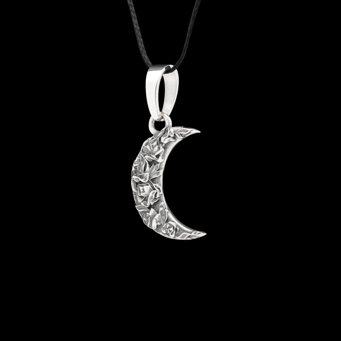 Sterling silver crescent Moon pendant with delicate roses, "Moonlit Rose" design, on a black background.