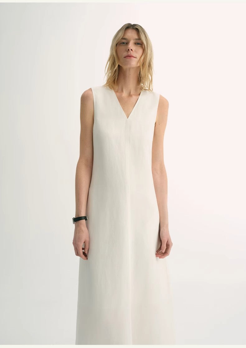 Model wearing Aurevae Cupro-Linen A-Line Dress in white with V-neck and sleeveless bodice, showcasing lightweight fabric and mid-calf silhouette.