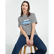 Model wearing gray Zalmera women's cotton t-shirt with customizable print design, seated on a wooden stool against white background.