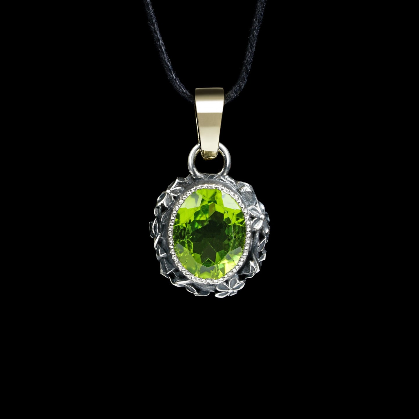 Enchanted Bloom pendant with oval peridot, oxidized sterling silver flowers, and 14K yellow gold clasp against black background.