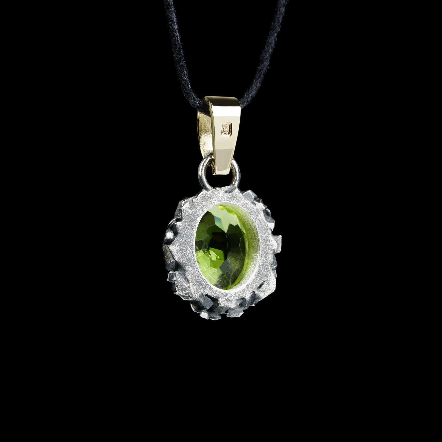 Enchanted Bloom Pendant with oval peridot centerpiece, surrounded by intricate silver flowers and a 14K gold clasp, on a black cord.