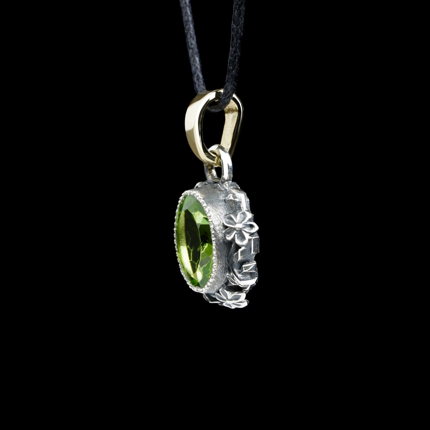 Handcrafted Enchanted Bloom pendant with green peridot, sterling silver flowers, and 14K gold clasp on black background