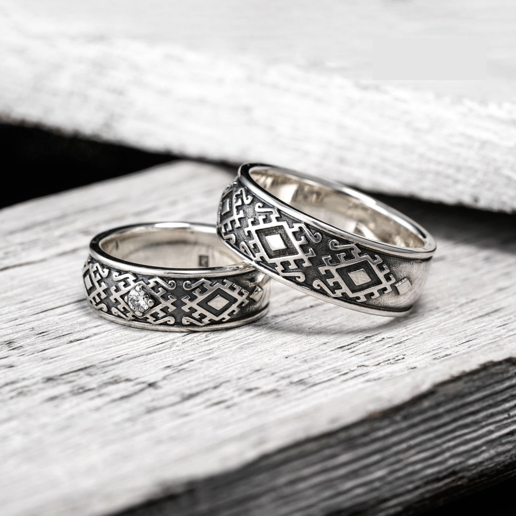 Carpathian Harmony sterling silver wedding rings with Hutsul-inspired designs and natural diamond on rustic wood background