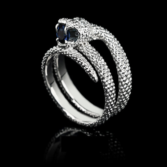 White gold ring with sapphire and diamonds, featuring a serpent design, symbolizing transformation and wisdom.