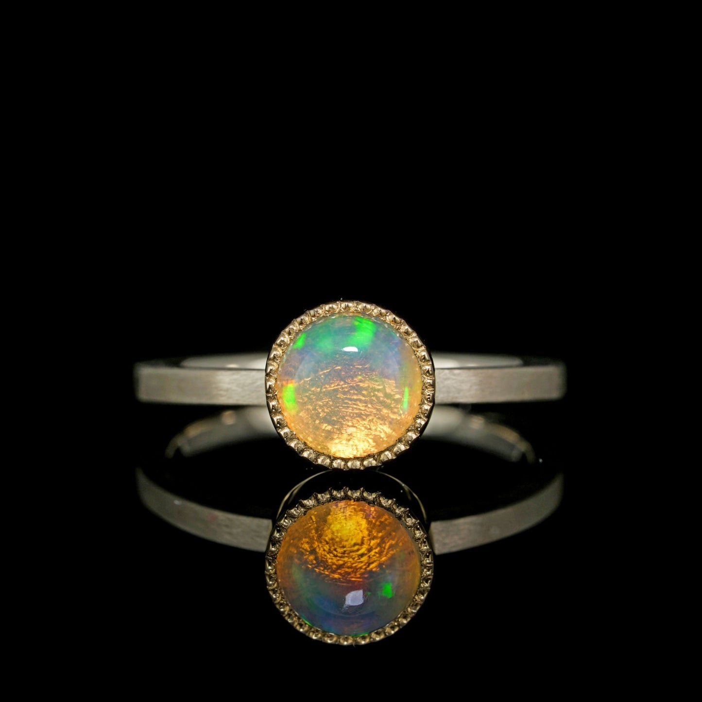 "Celestial Orbit ring showcasing a shimmering opal set in two-tone white and 14K yellow gold, reflecting cosmic elegance and beauty."