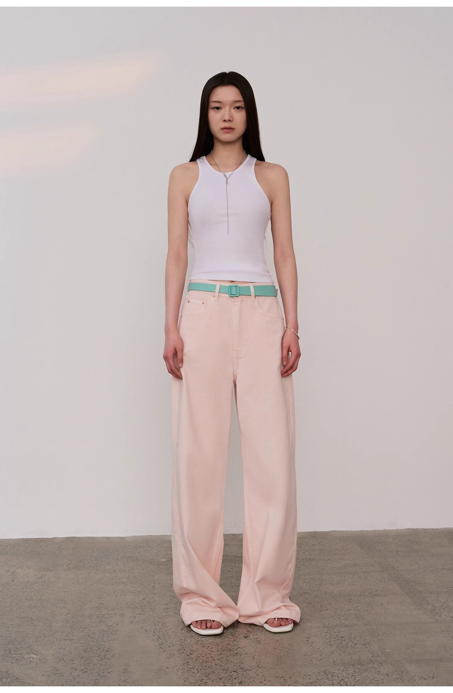 Woman wearing Isvera Slim Cotton Camisole paired with pastel pink wide-leg pants and turquoise belt, showcasing fashionable summer look.