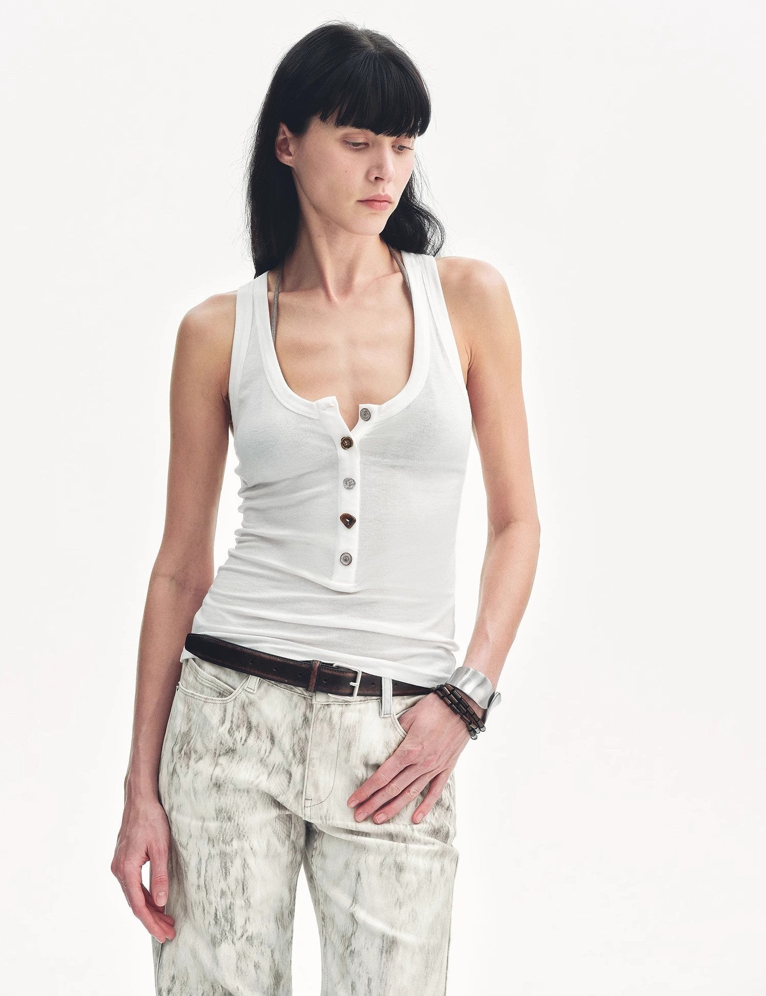 Woman wearing Lureva U-Henley Vest with minimalist design, wide-strapped neckline, and button details, paired with patterned pants.