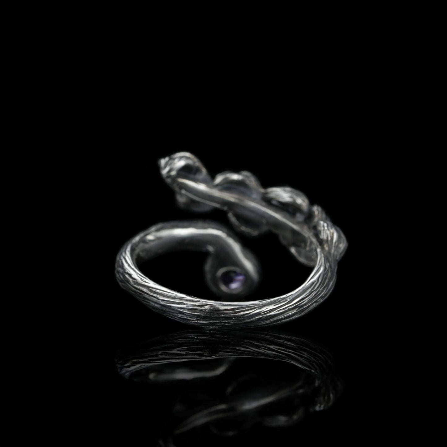 Sterling silver Blossom Symphony ring with white rhodium plating and amethyst accent, showcasing elegant craftsmanship against a black background.