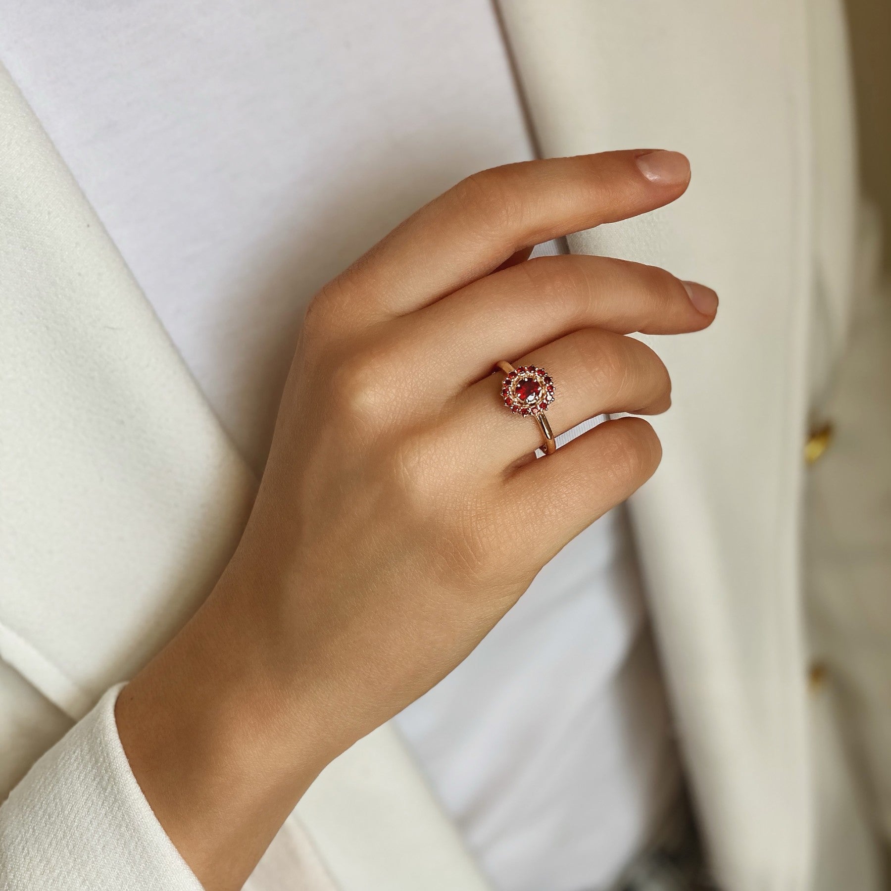 Elegant hand wearing Fiery Allure ring in red 14K gold with garnets, showcasing timeless beauty and luxury.