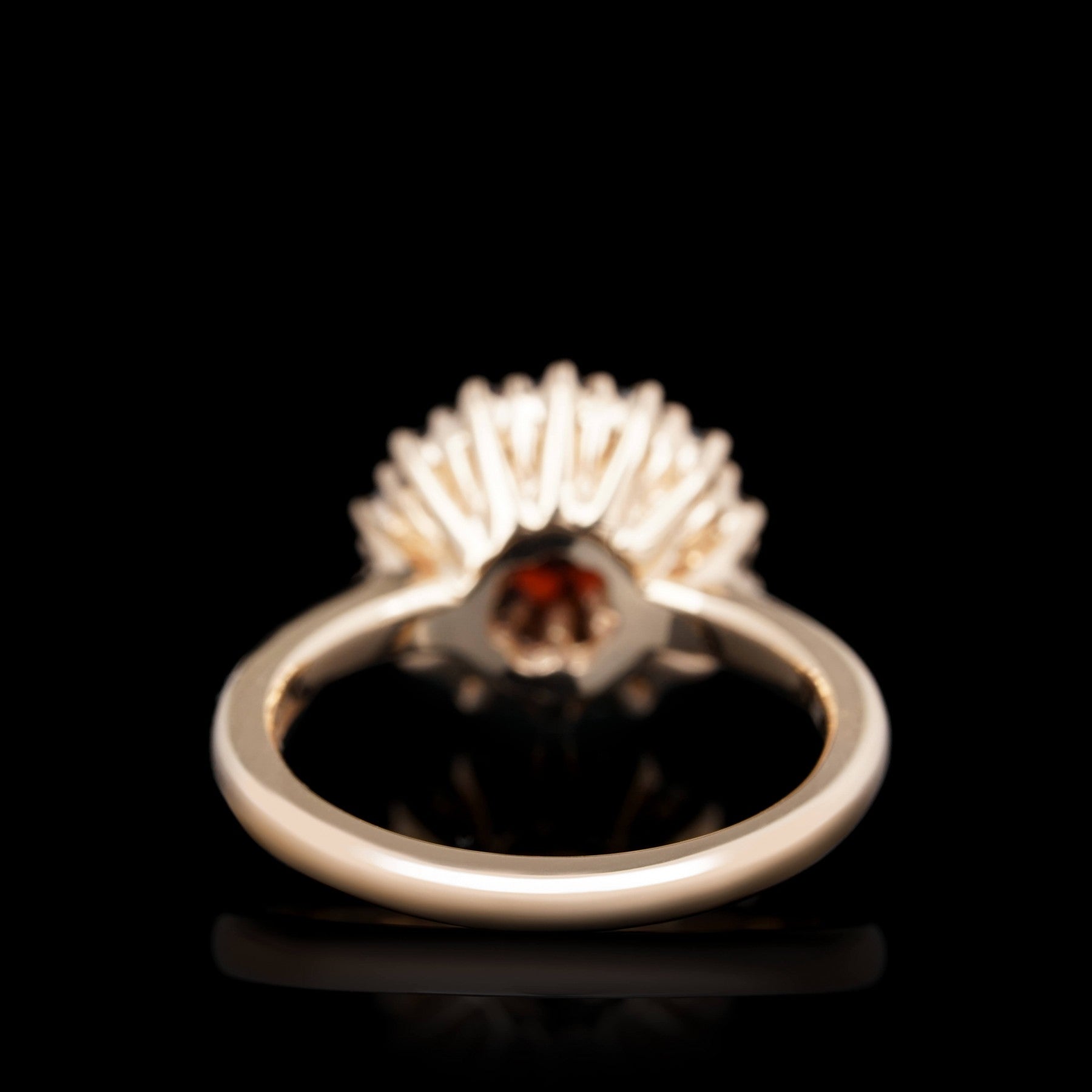 Fiery Allure ring side view in red 14K gold with garnet centerpiece showing detailed craftsmanship against a black background.